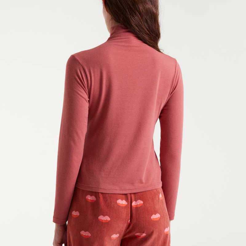 Person wearing a pink long-sleeve top and heart-patterned pants on a white background