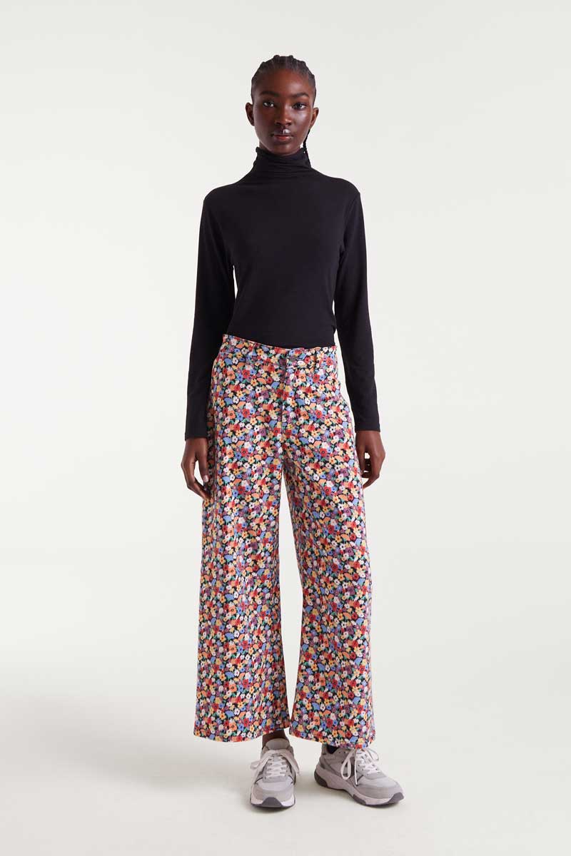 Person wearing a black turtleneck and colorful patterned pants on a white background