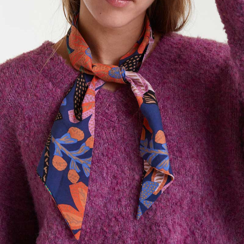 Person wearing a colorful patterned scarf on a plain background