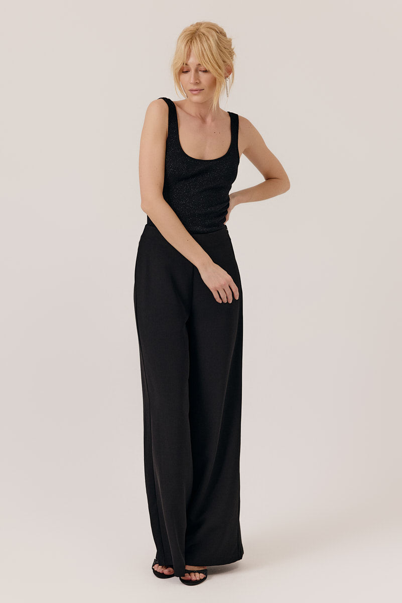 Woman wearing a black sleeveless jumpsuit on a white background