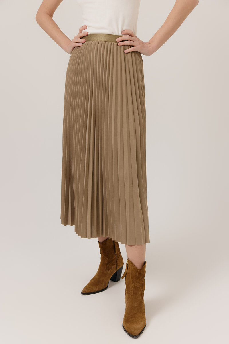 Person wearing a beige pleated skirt and brown boots on a white background