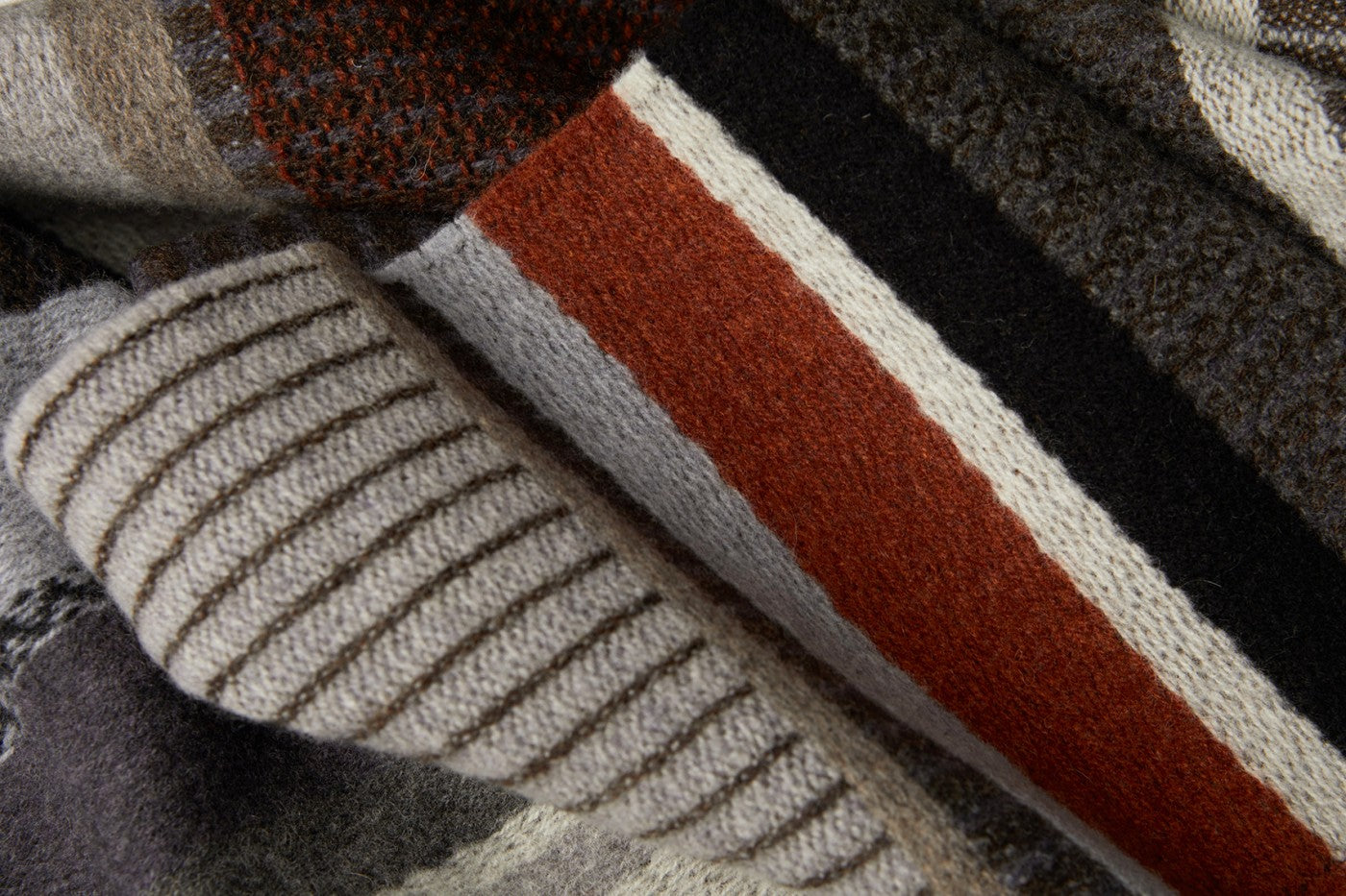 Close-up of a knitted textile with horizontal stripes in shades of gray, brown, and rust.