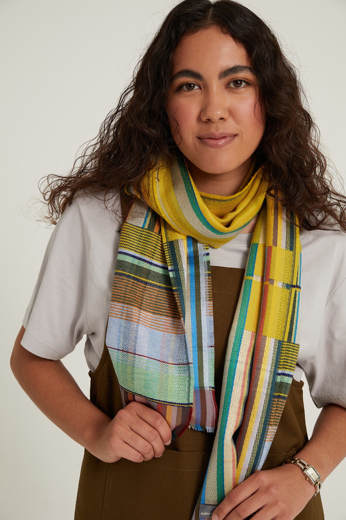 Multicolored woven scarf with predominantly yellow and teal stripes and plaid patterns.