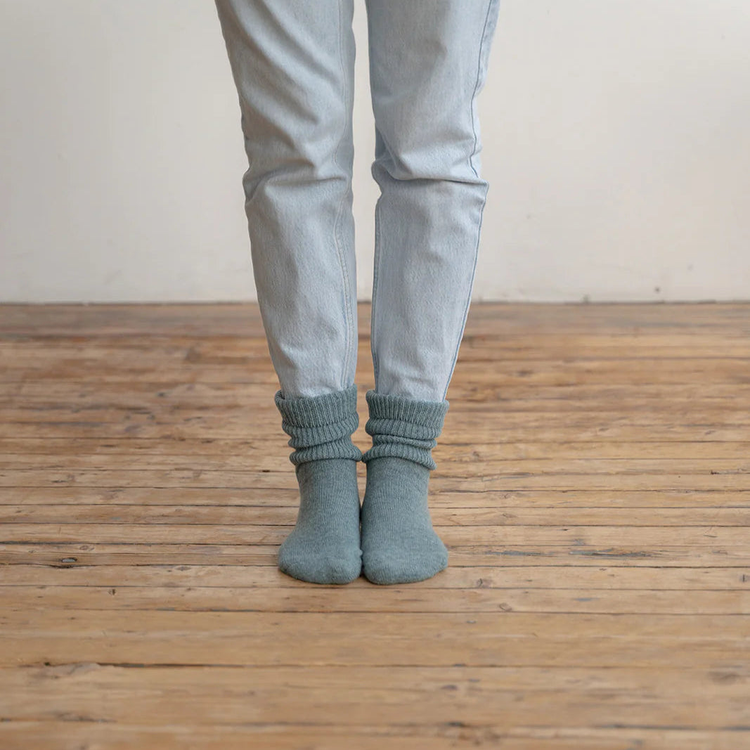 Person wearing light gray pants and dark gray socks on a wooden floor.