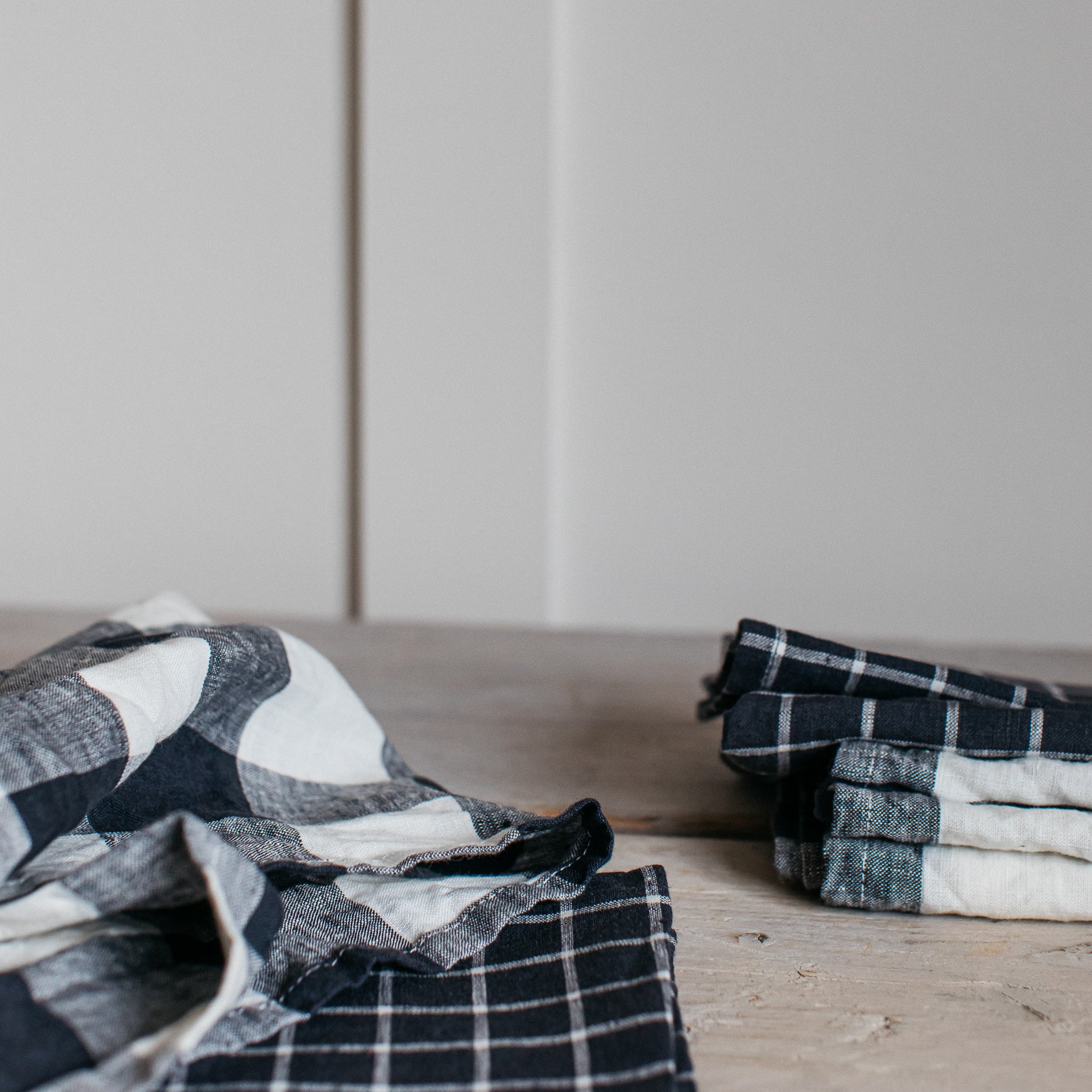 Black and white checkered linen tea towels, one folded loosely, another neatly stacked.