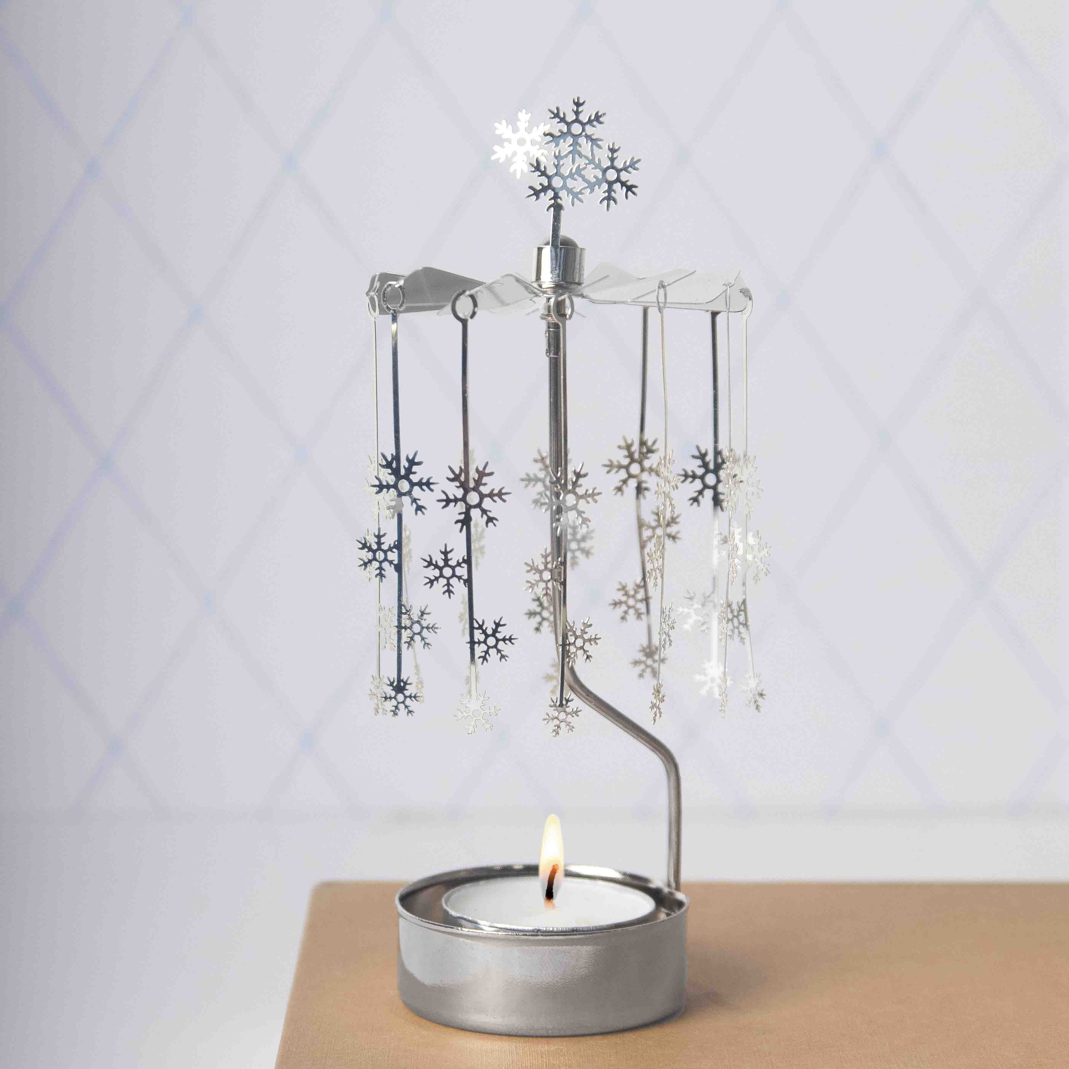 Decorative metal candle holder with snowflake designs on a light background