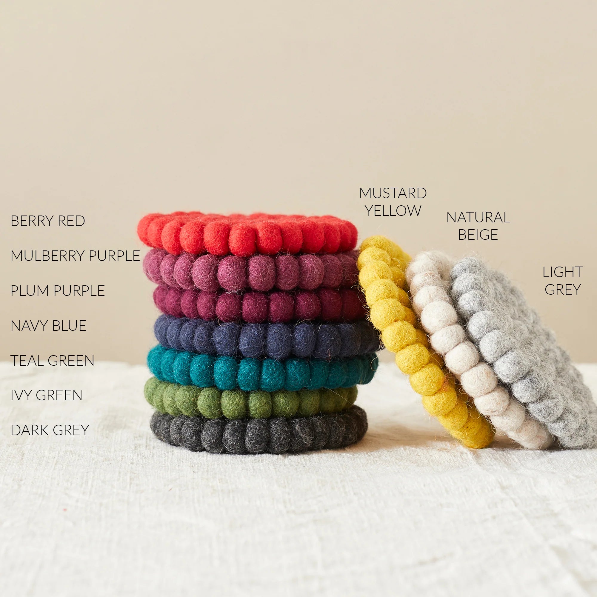 Stack of colorful felt coasters in various shades of red, purple, blue, green, and gray.