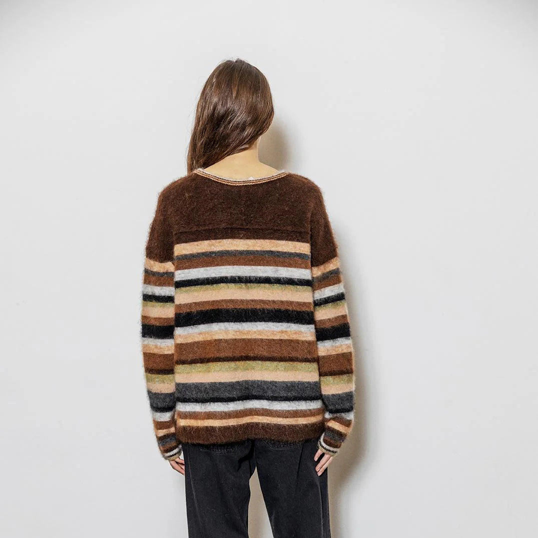 Person wearing a striped sweater with a plain background