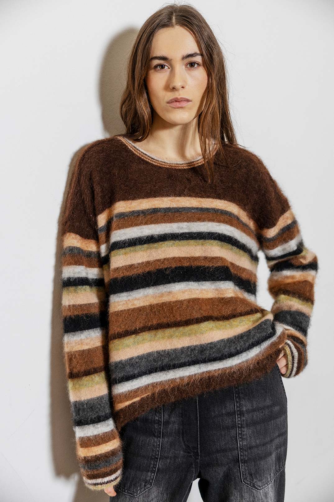 Person wearing a brown striped sweater against a white background
