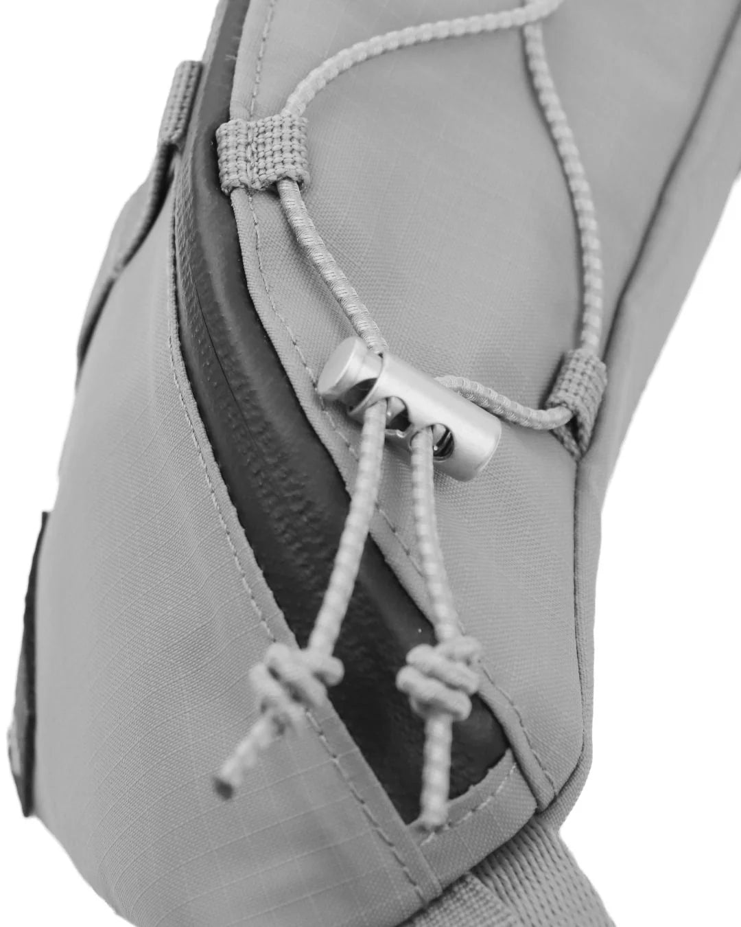 Close-up of a gray fabric bag detail, showing adjustable cord closures with metal toggles and a contrasting black seam.