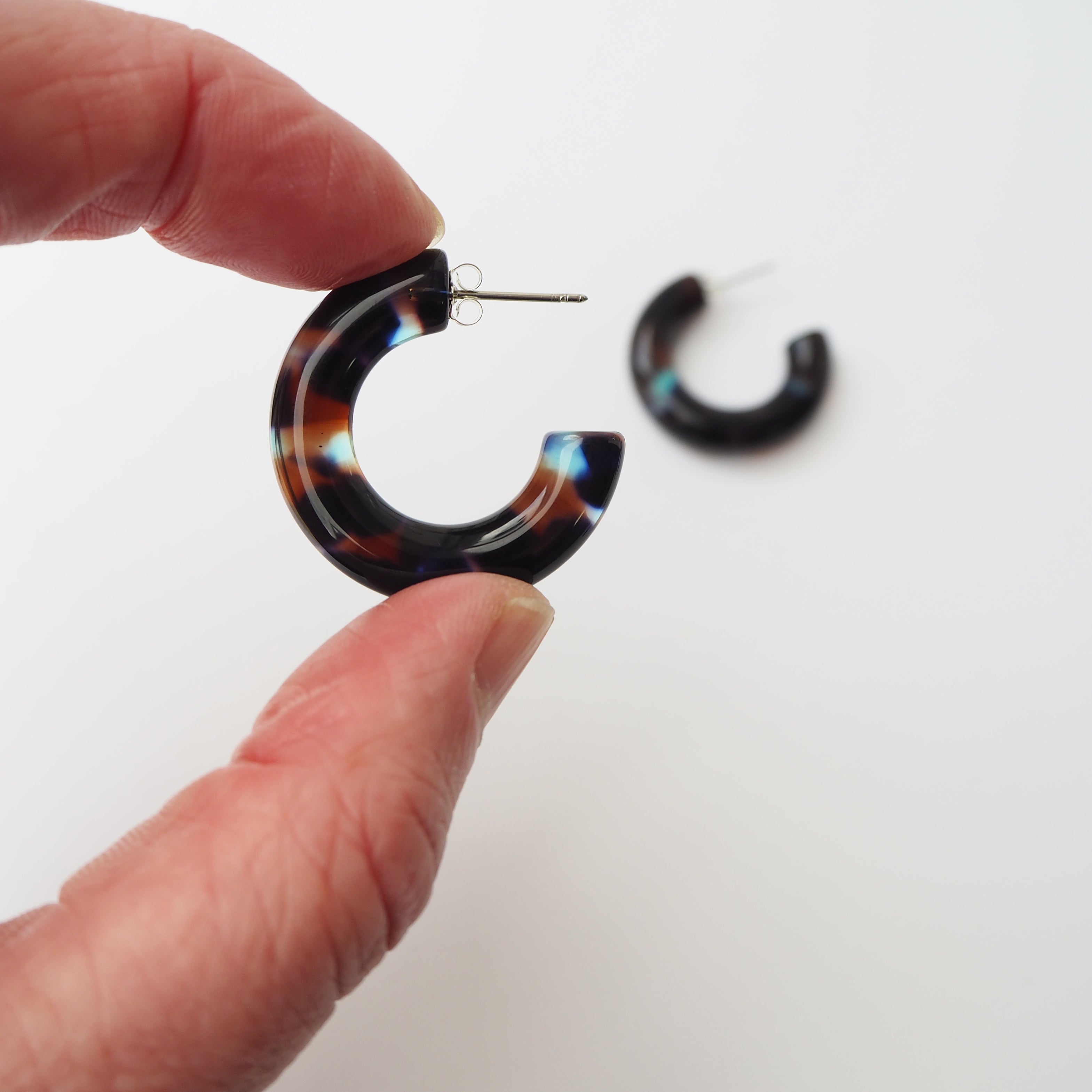 Pair of dark tortoiseshell hoop earrings.  The hoops are thick and slightly irregular in shape.