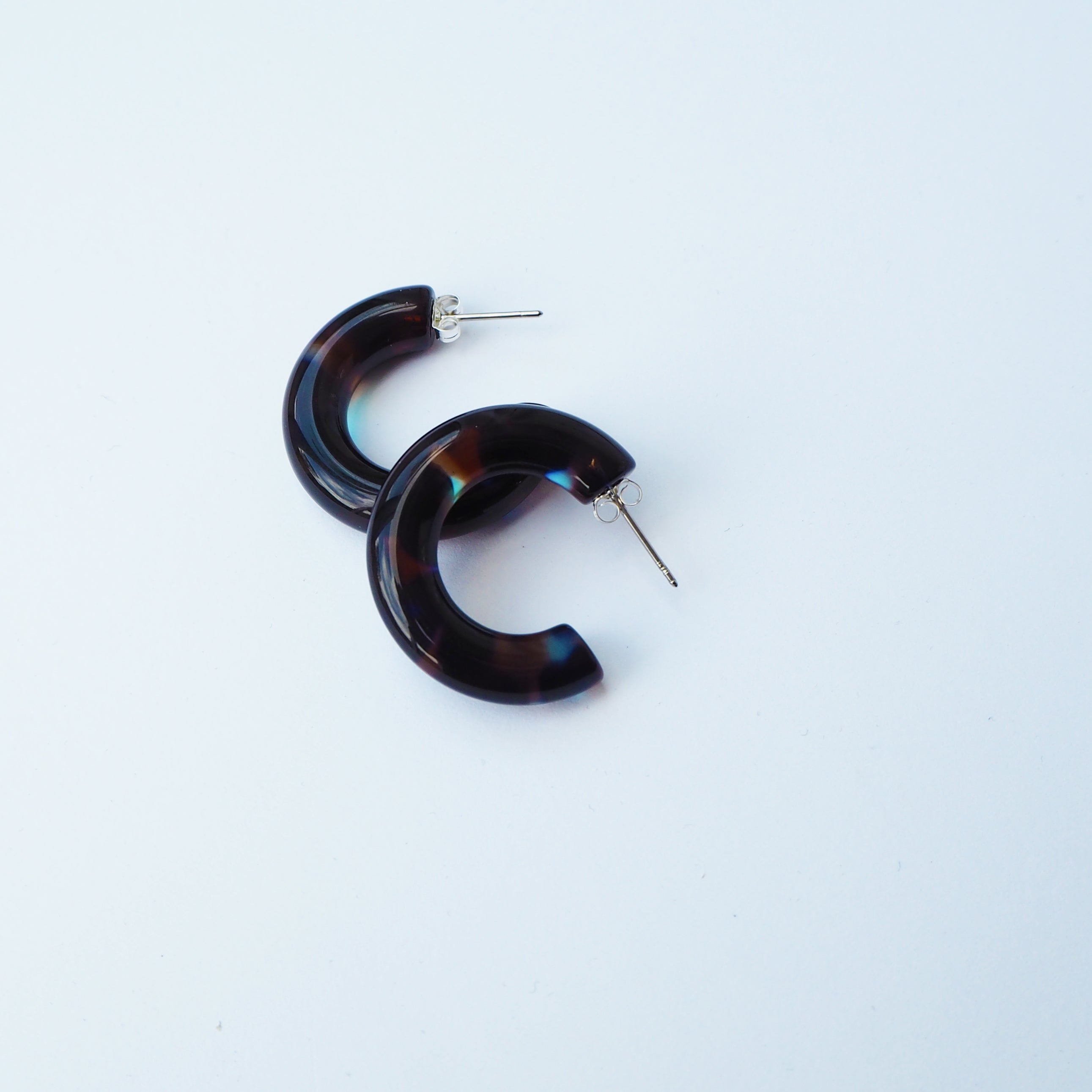 Pair of dark tortoiseshell hoop earrings with silver posts.