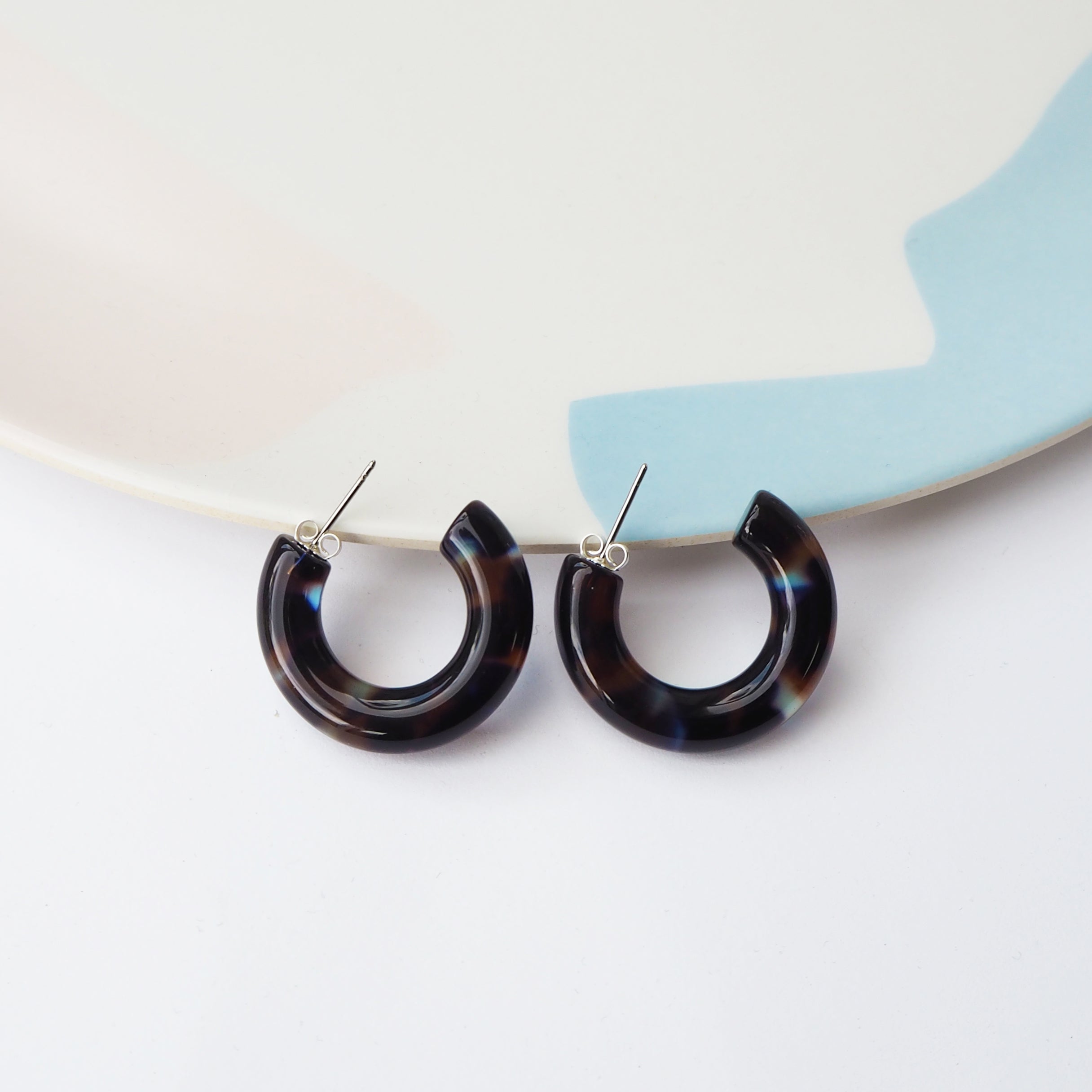 Pair of dark tortoiseshell hoop earrings with silver posts.