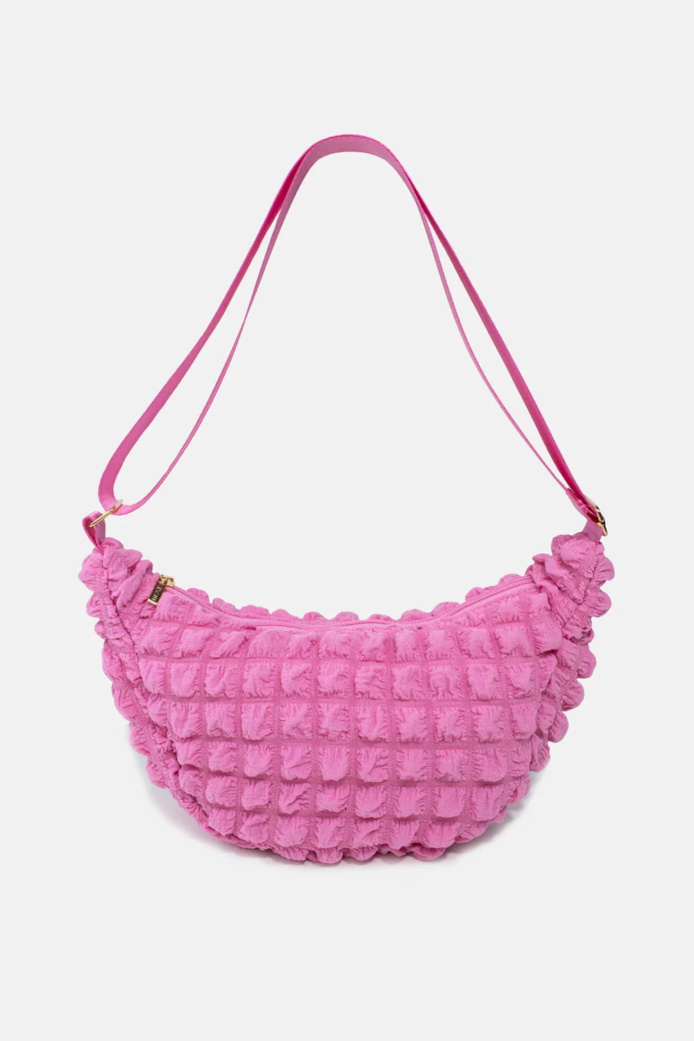 Pink quilted half-moon crossbody bag with a long strap and zipper closure.