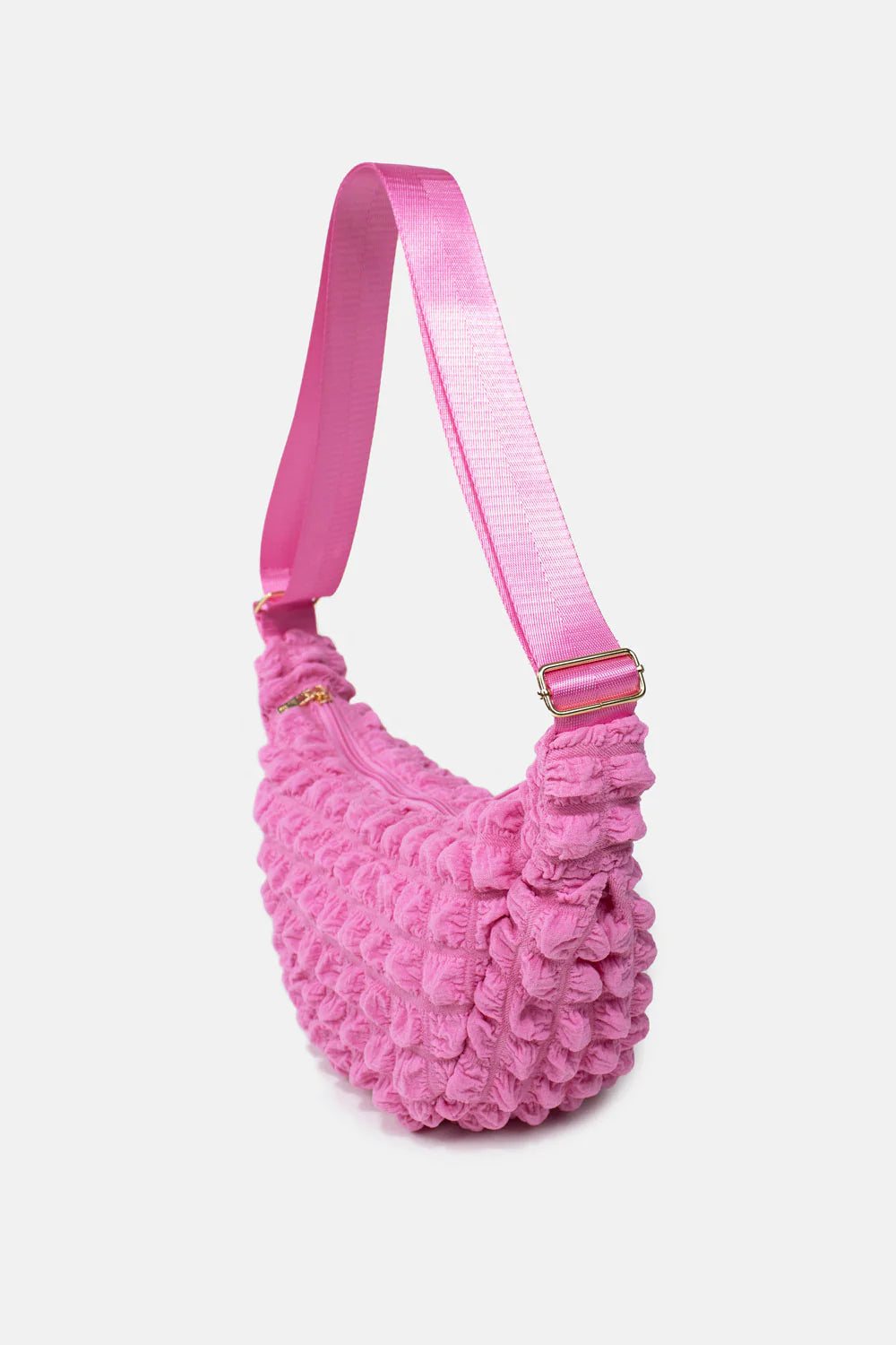 Pink textured half-moon crossbody bag with a pink adjustable strap and gold zipper.