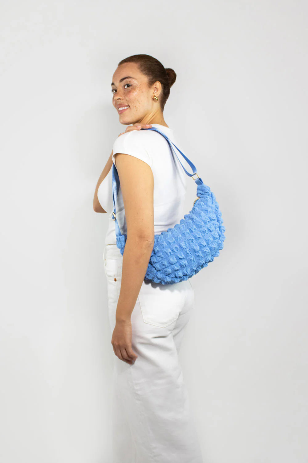 Light blue textured half-moon crossbody bag with a shoulder strap.