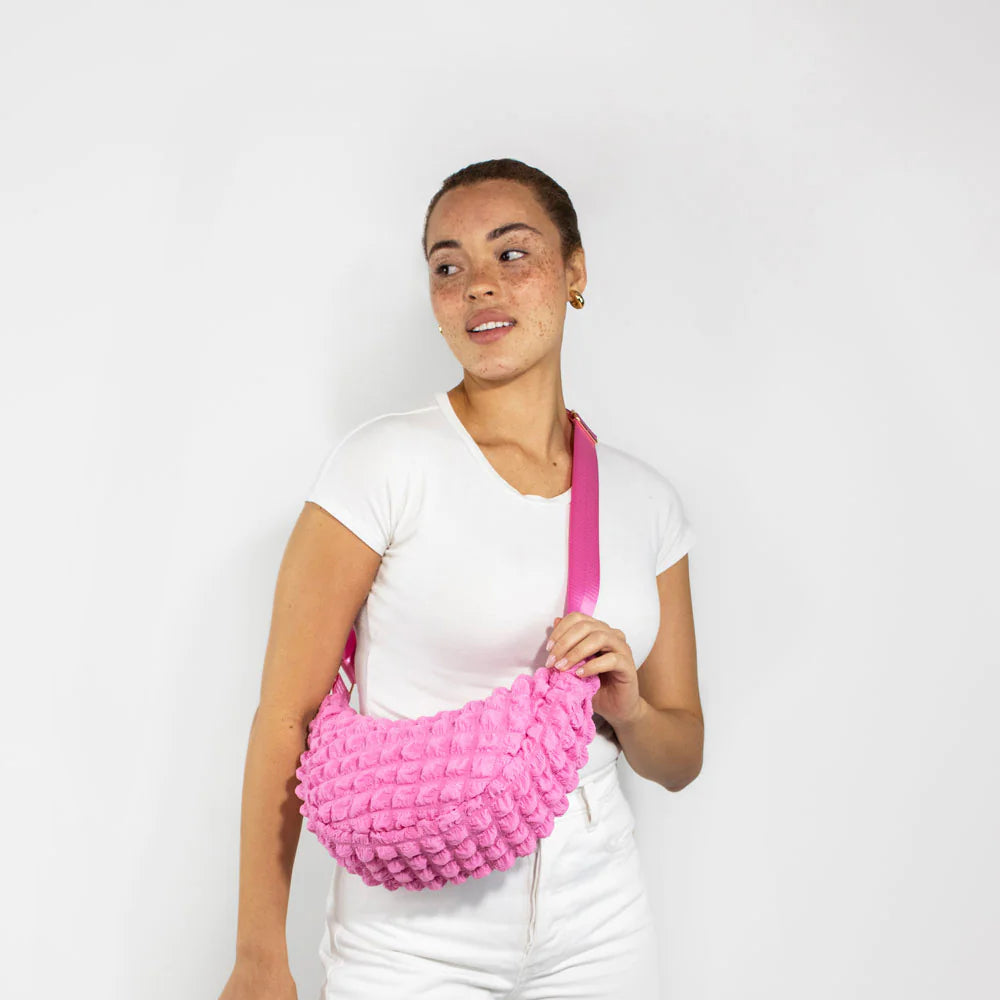 Pink textured crescent-shaped crossbody bag with a hot pink strap.