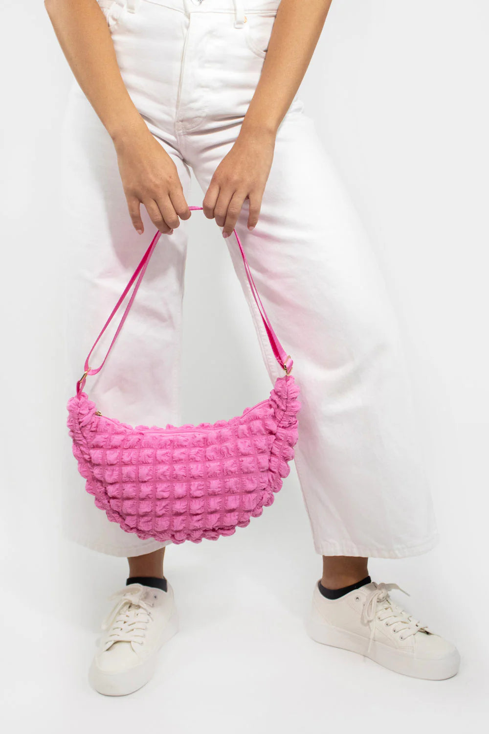 Pink textured half-moon crossbody bag with pink straps.
