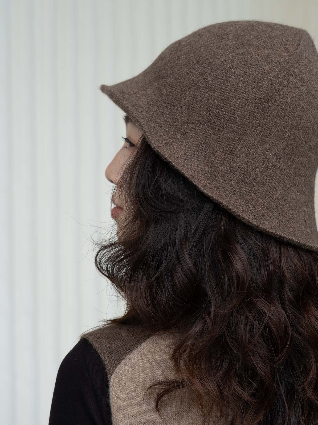 Person wearing a brown bucket hat against a white background