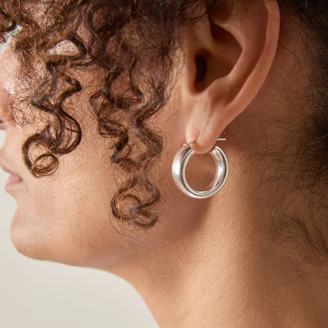 Silver hoop earrings; thick, slightly rounded band.