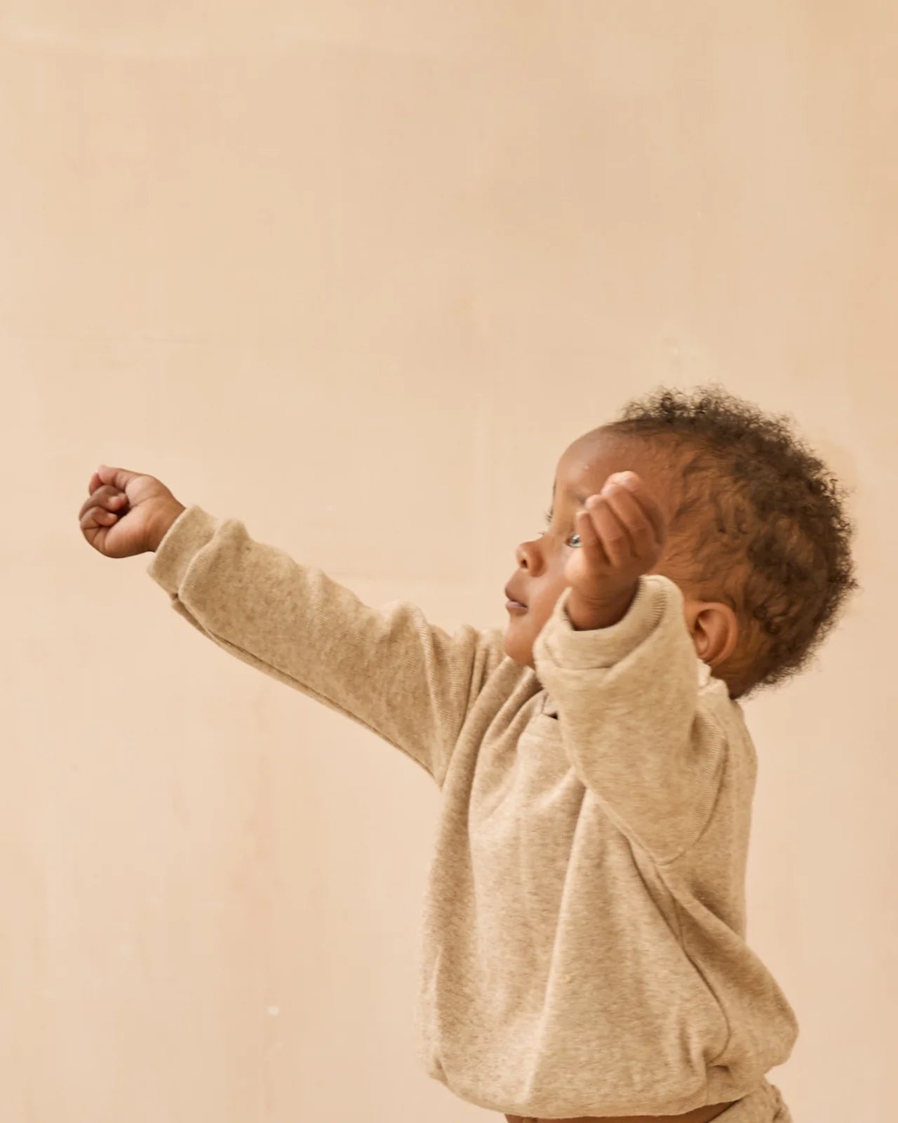 Child wearing a beige sweater against a beige background