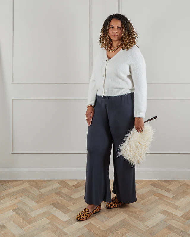 Off-white fluffy cropped cardigan, dark gray wide-leg trousers, and leopard-print loafers.