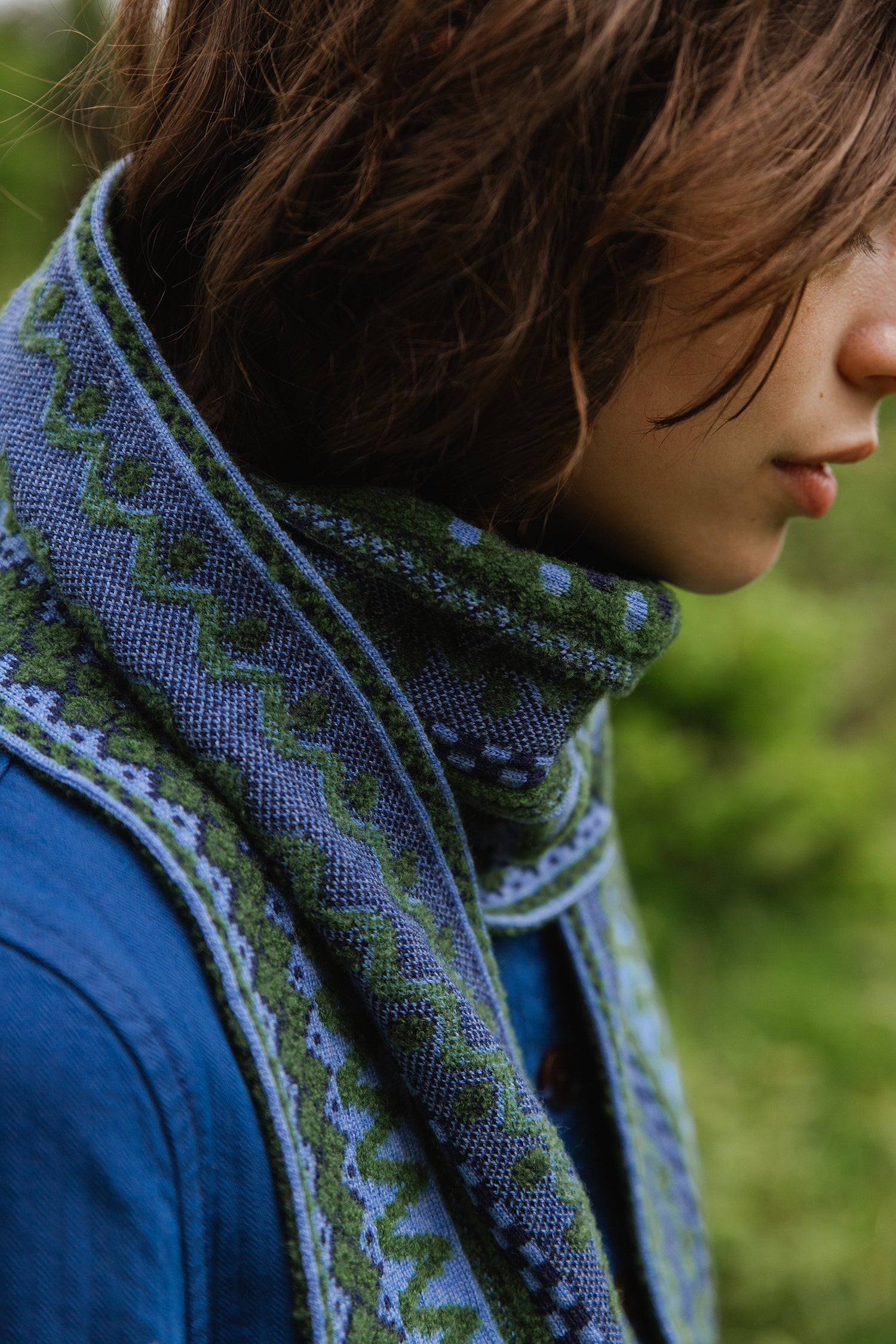 Woven scarf in shades of blue and green, featuring a geometric pattern.