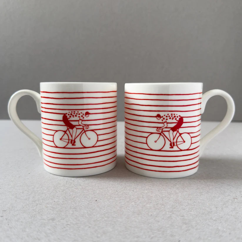 Two white mugs with red horizontal stripes and a cyclist on a bicycle design.