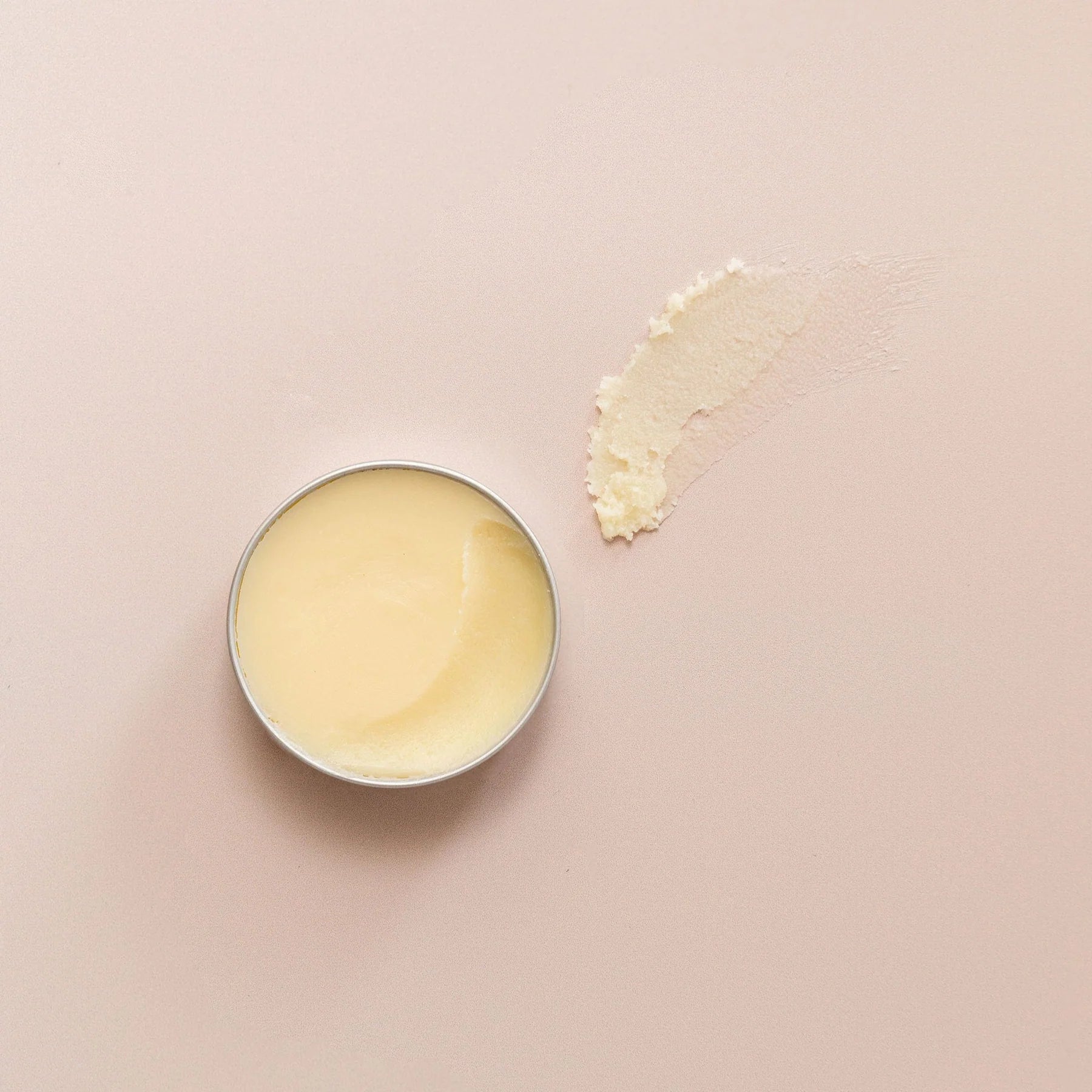 Pale yellow balm in a silver tin, with a smear of the balm next to it.