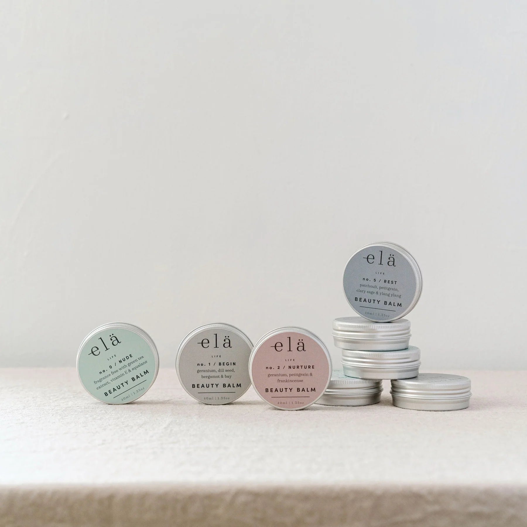 Four elá Life Beauty Balms in silver tins;  Nude, Begin, Nurture, and Rest.