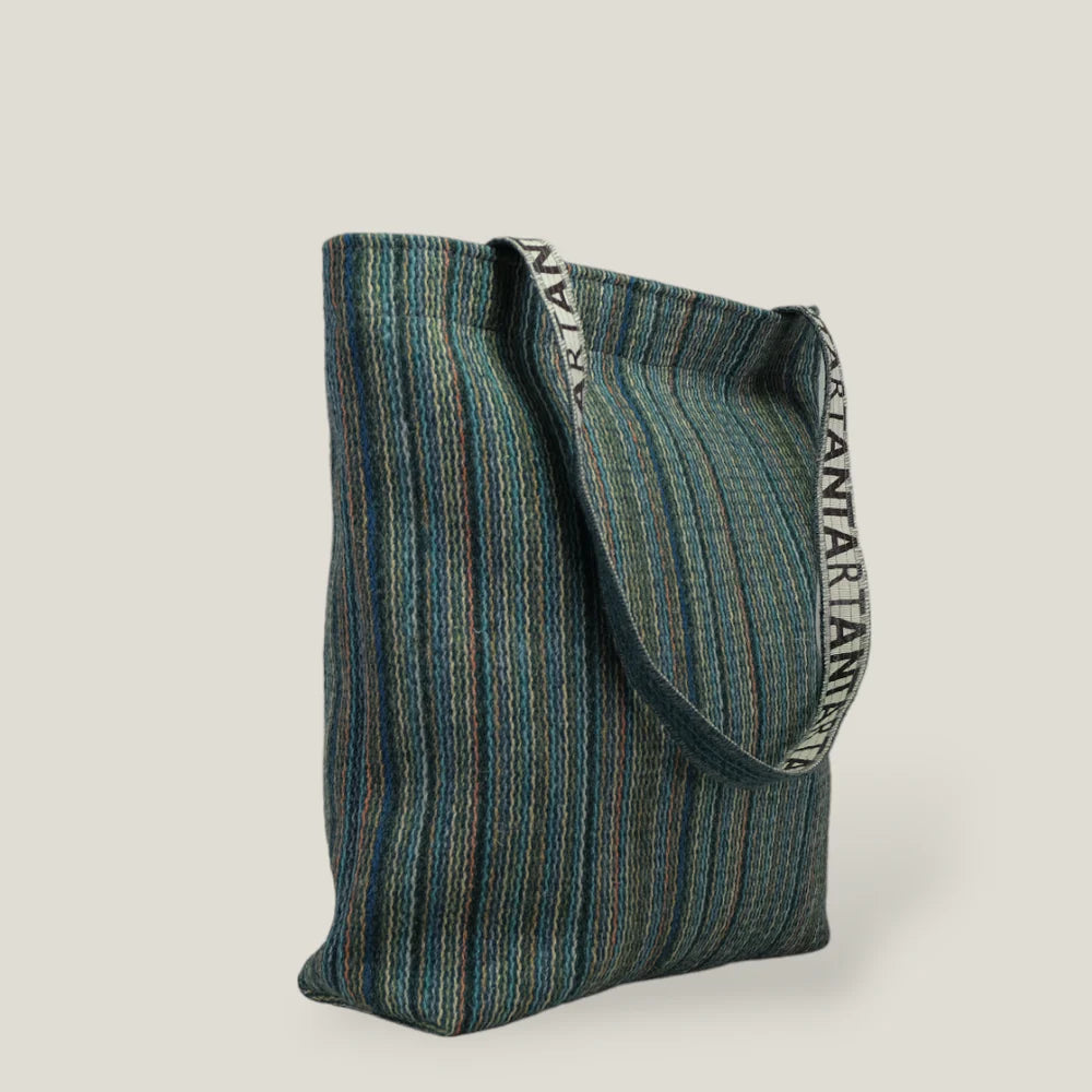 Striped teal tote bag with fabric handles and "ARTANIA" lettering on the straps.