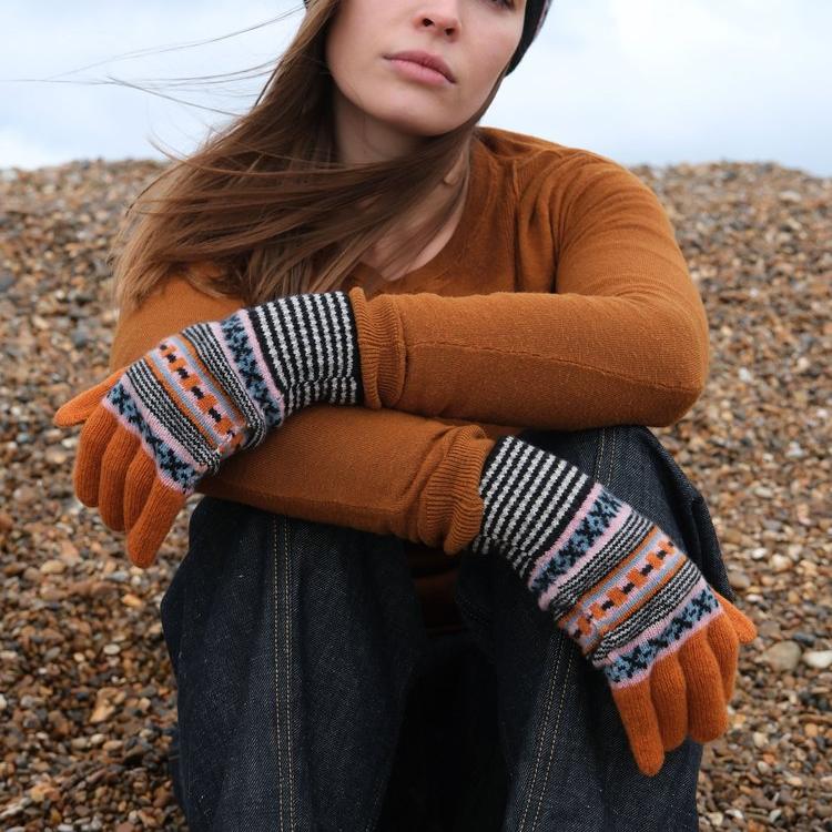Fair isle patterned fingerless gloves in orange, black, white, and teal.