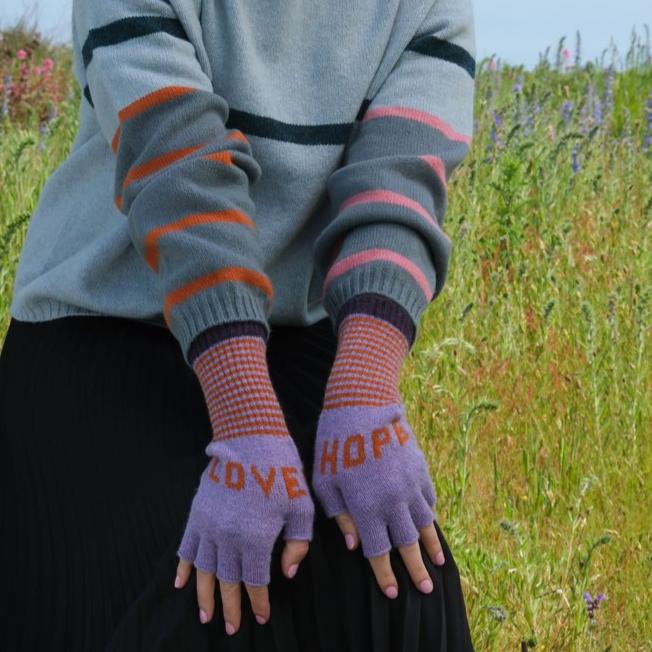 Pair of purple fingerless gloves with "LOVE" and "HOPE" embroidered on them in orange.