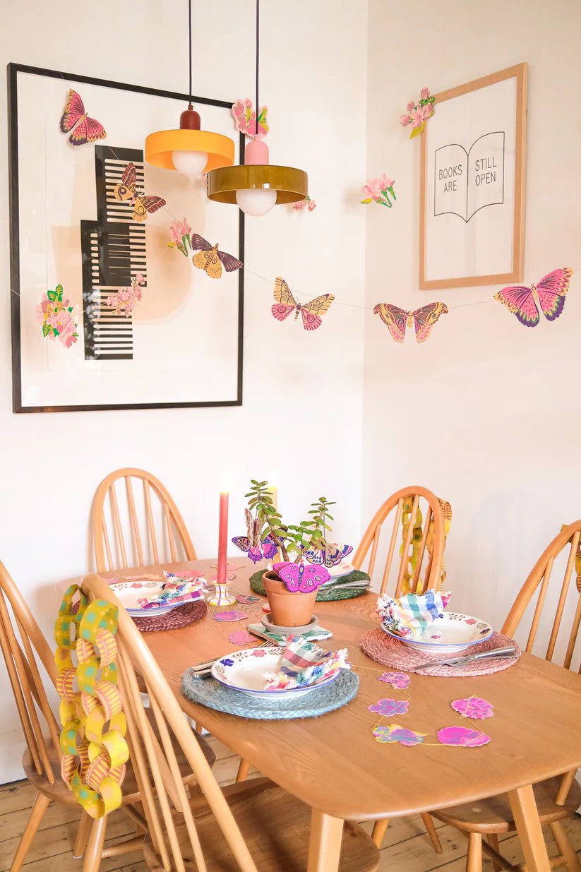 Dining table setting decorated with butterfly garlands and colorful place settings.