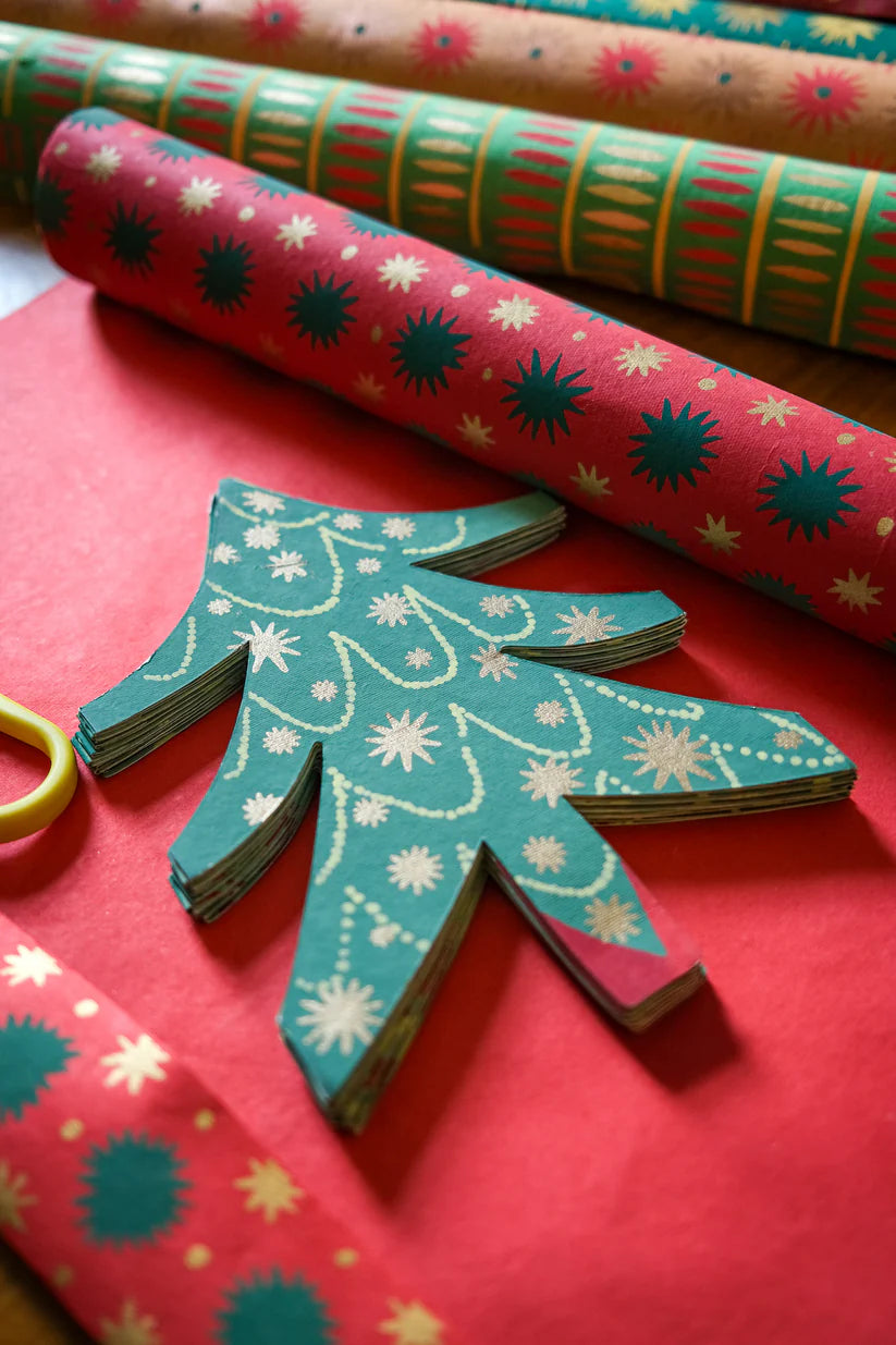 Colorful patterned paper rolls with a hand-shaped cutout on a red surface