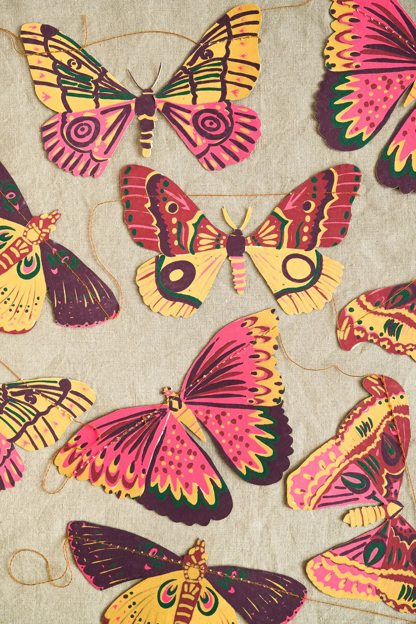 Garland of colorful paper moths with pink, yellow, and maroon patterns.