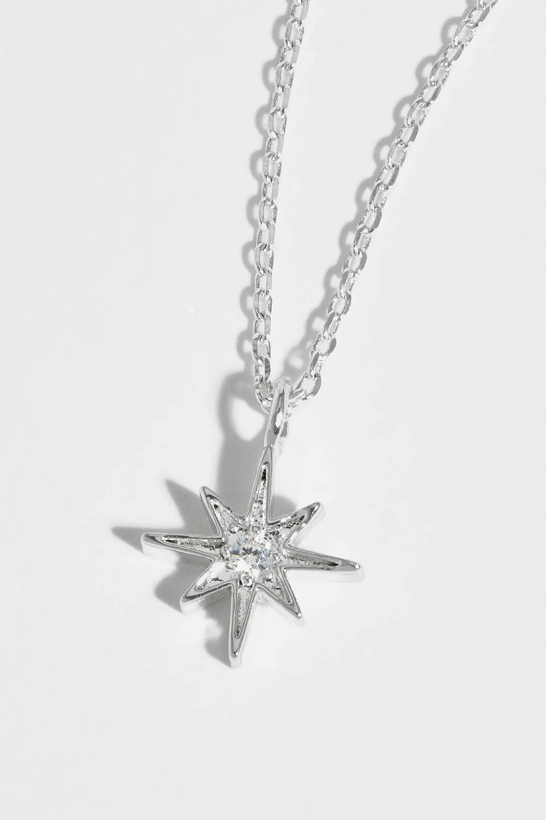 Silver necklace with a star-shaped pendant featuring a central clear stone.
