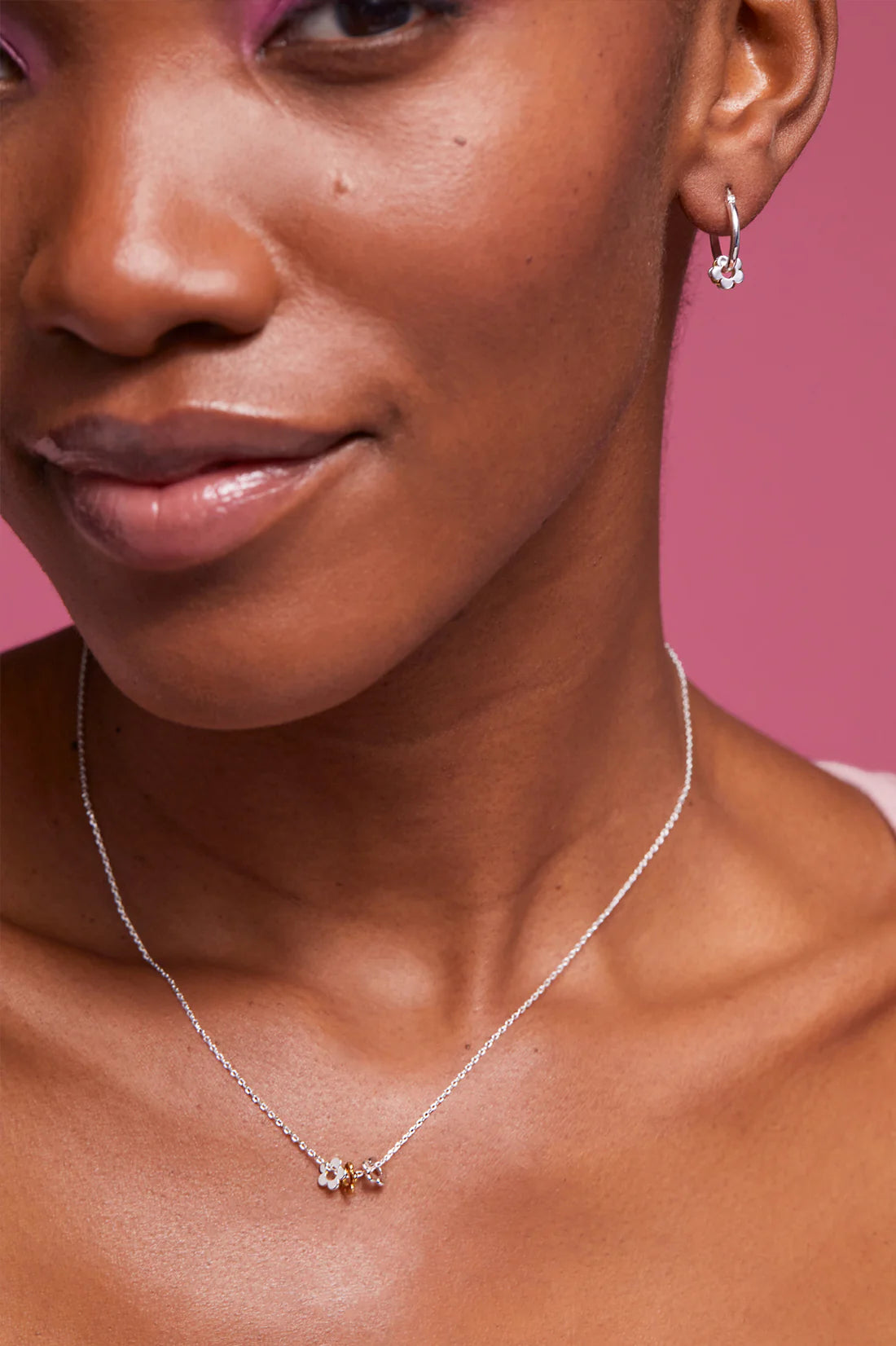Silver necklace featuring three small flower charms; two silver, one gold. Matching silver flower hoop earrings also shown.
