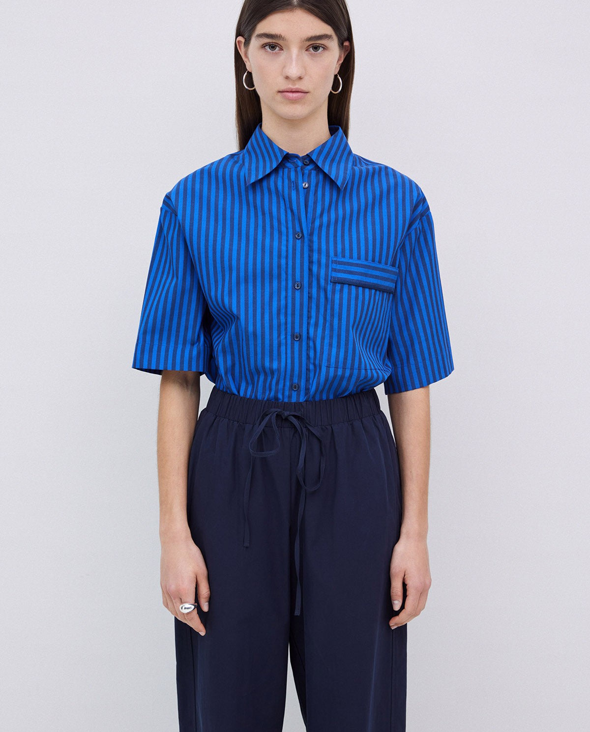 Blue vertically striped short-sleeve collared shirt with a chest pocket, paired with dark navy drawstring pants.
