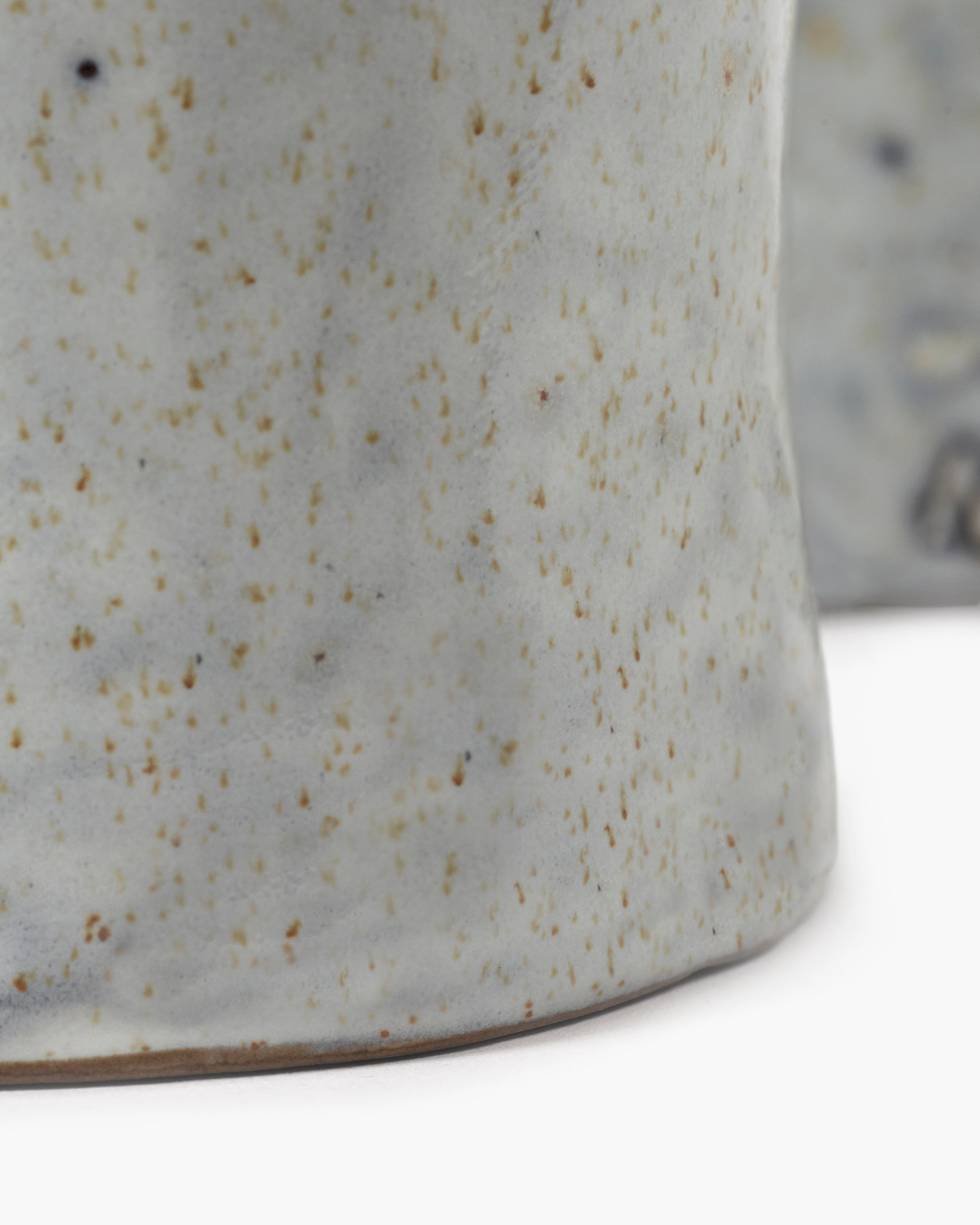 Close-up of a light grey ceramic mug with speckled brown glaze.  The mug has a slightly irregular, handmade appearance.