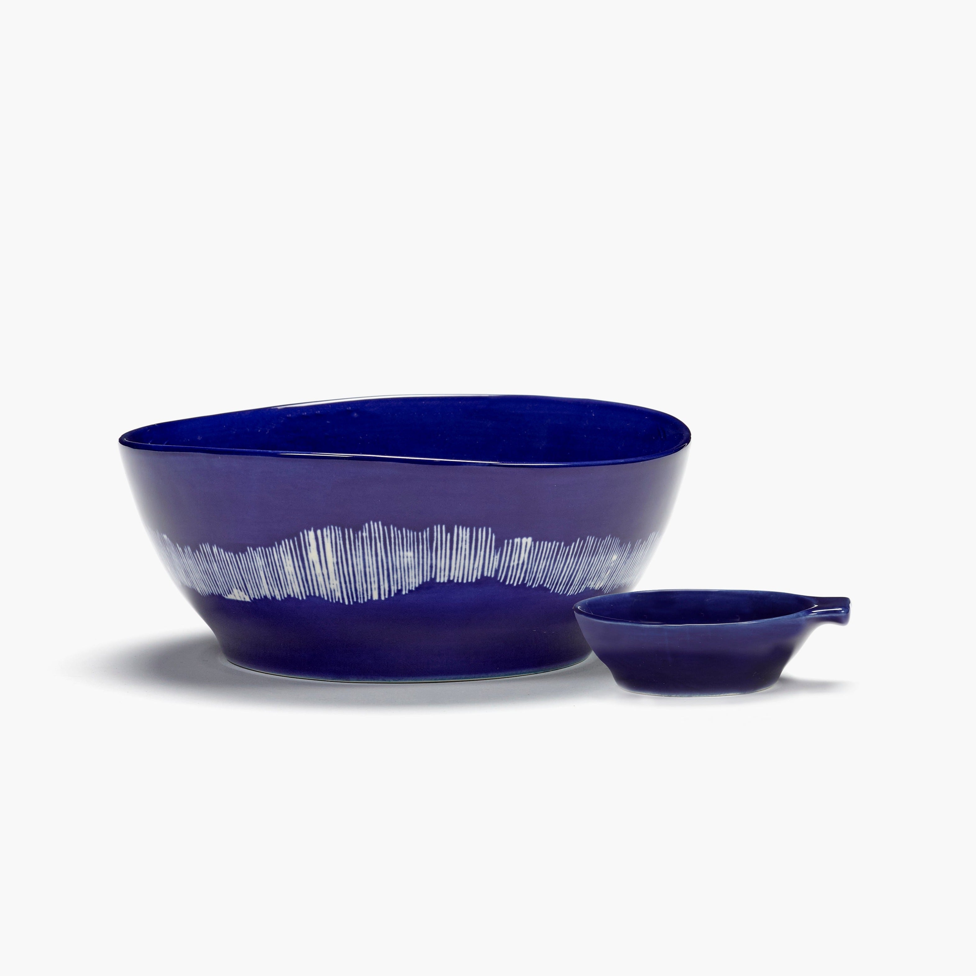 Dark blue ceramic bowl and small dish with white linear design.