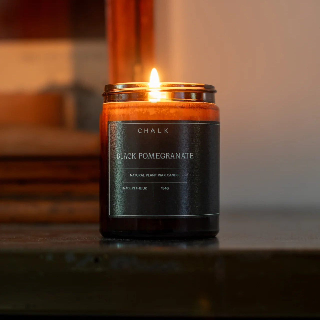 Candle labeled 'Black Pomegranate' by 'Chalk' on a dark surface with a blurred background