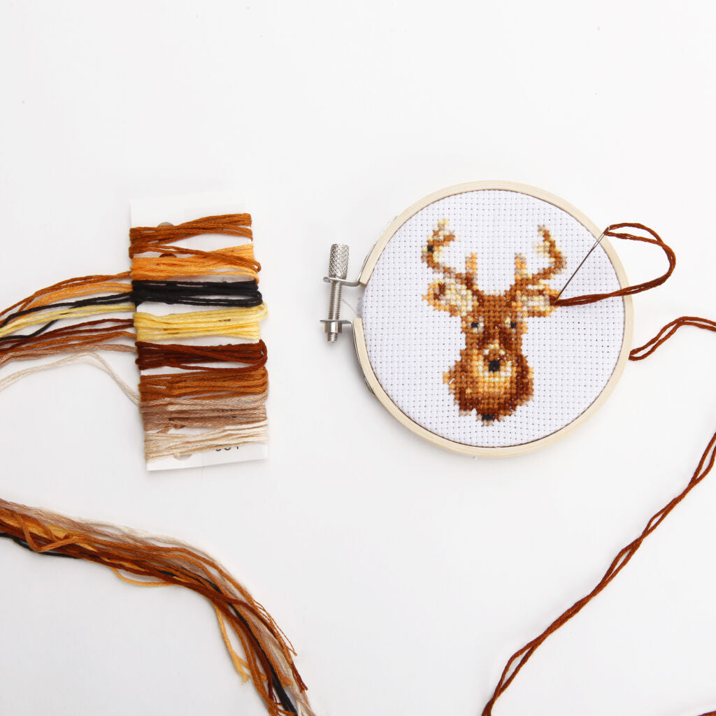Cross-stitch embroidery in progress depicting a deer's head, in earth tones, on a round hoop.