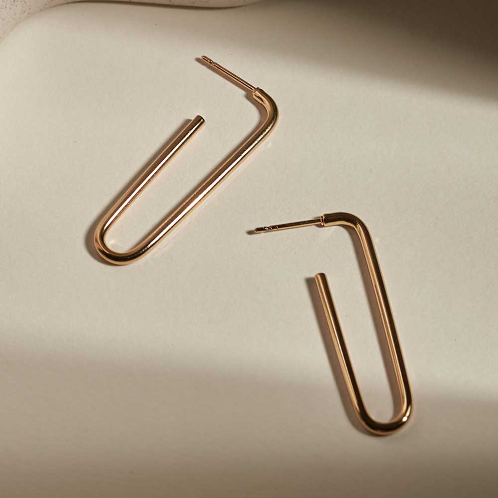 Pair of gold open-loop earrings. Simple, minimalist design with a smooth, rounded finish.