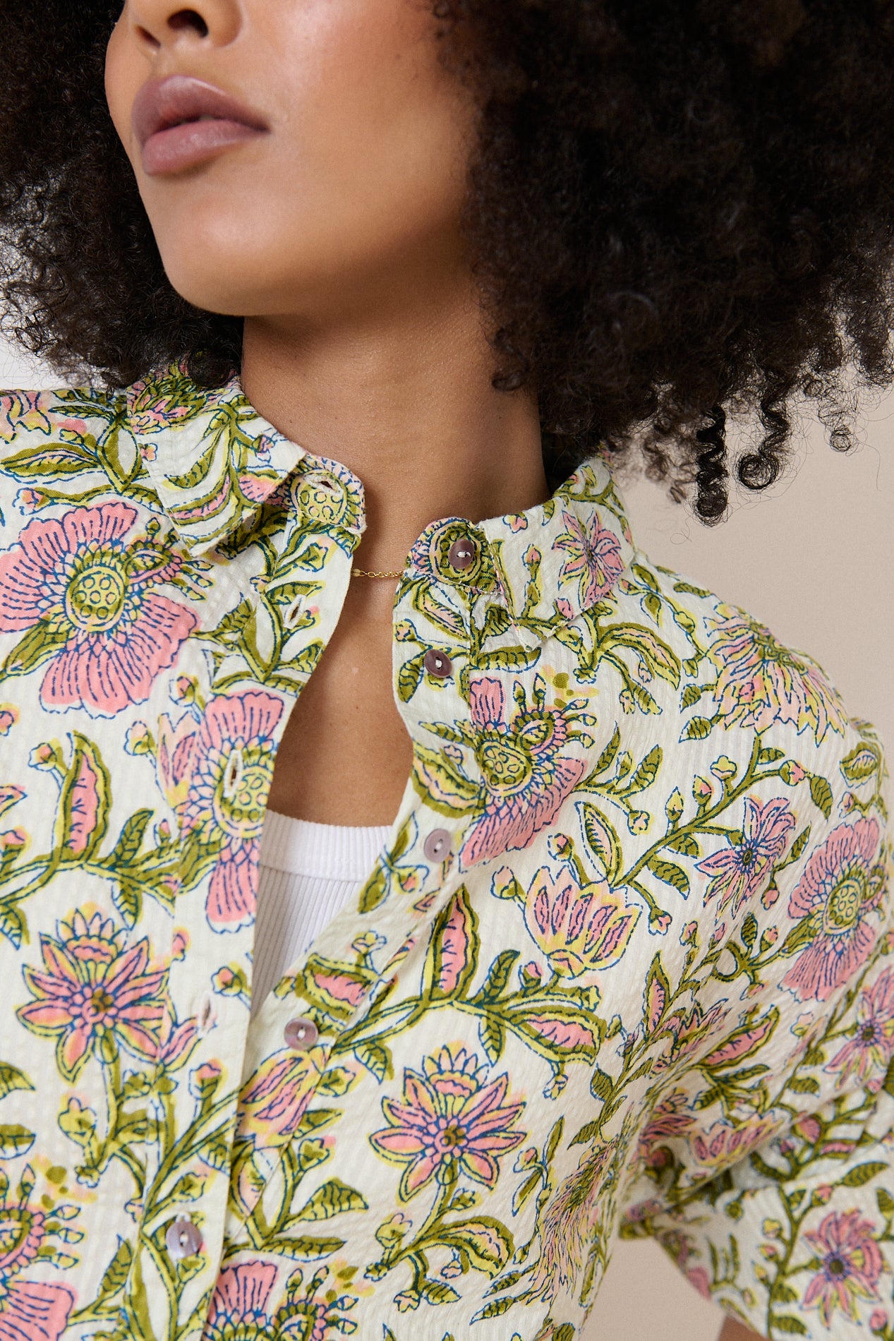 Cream-colored shirt with a floral print in shades of pink and green.