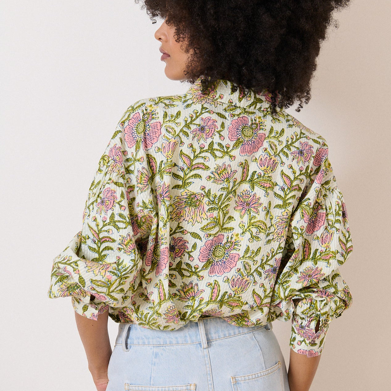 Off-white, floral-print shirt with puffed sleeves and a collared neckline.