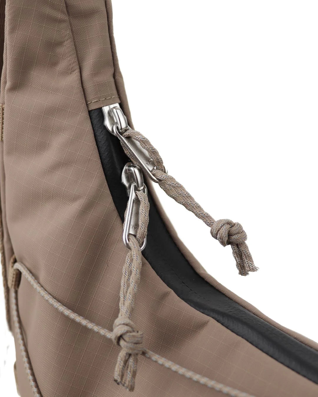 Tan crossbody bag with zipper closure and drawstring accents.