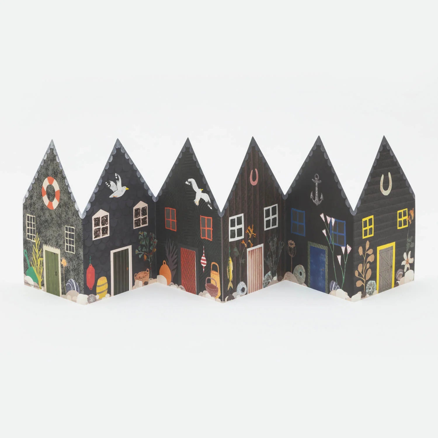 Folded paper model of a row of small, dark-colored houses with illustrated nautical details and colorful accents.