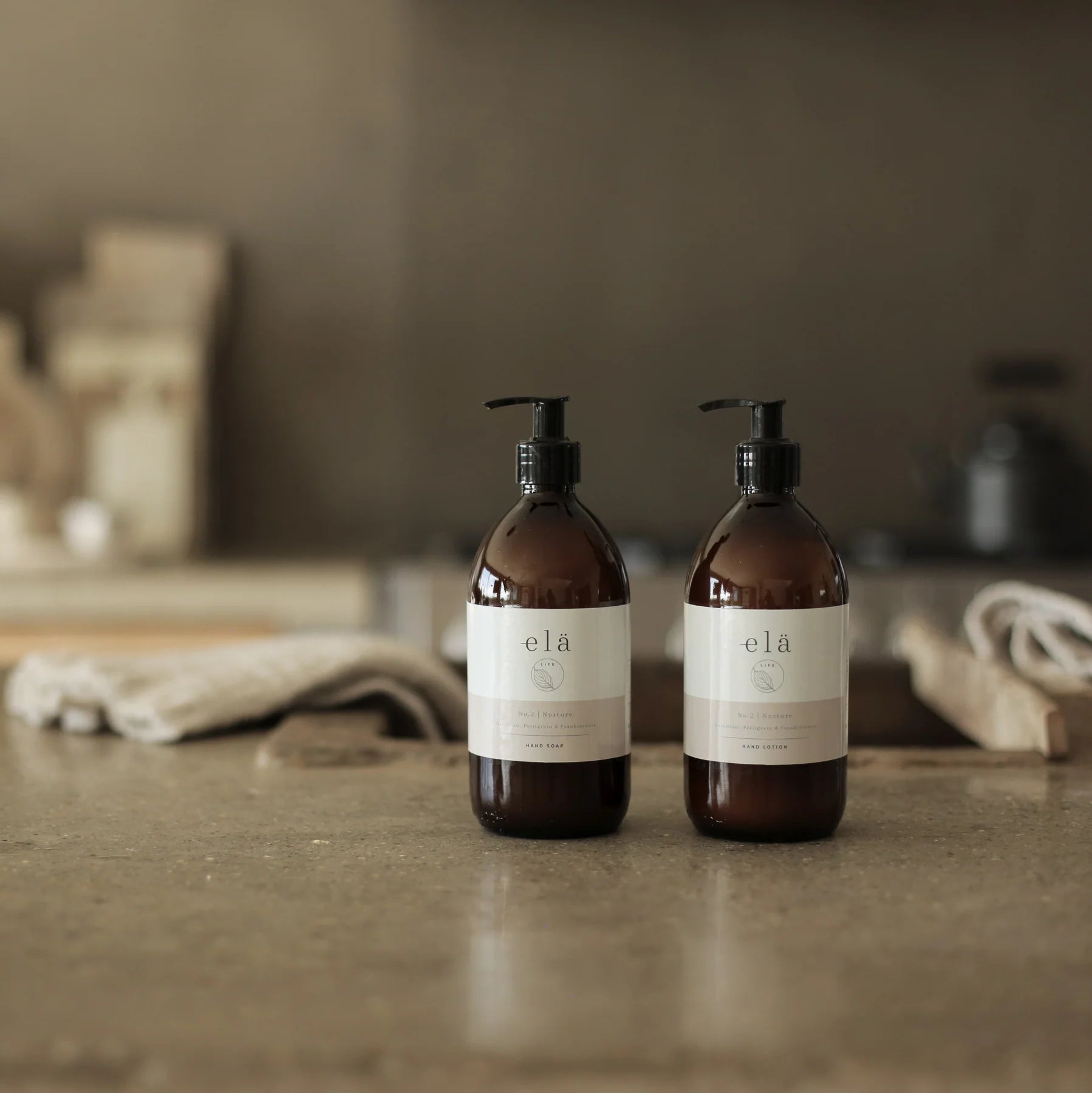 Two amber glass bottles of elá hand soap and hand lotion with pump dispensers.