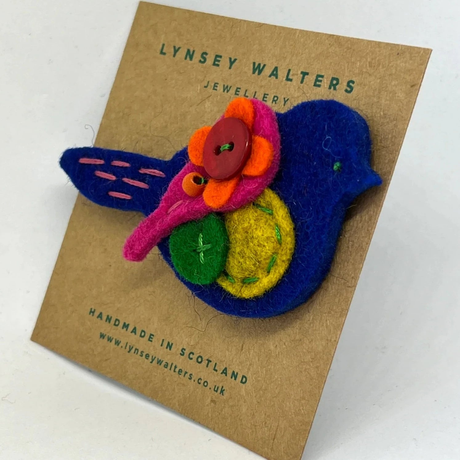 Handmade felt bird brooch with colorful flower detail. Bright blue, pink, orange, yellow, and green felt.